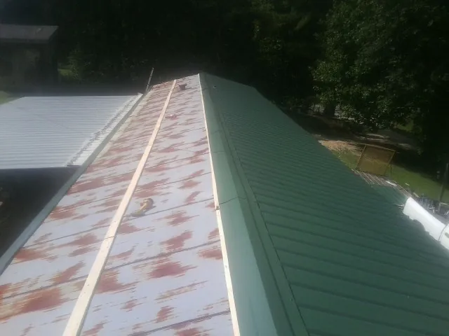 Old rusted panels beside newly installed green metal roofing — Wind Damage Roof Repair by Roofing Brothers in Codorus