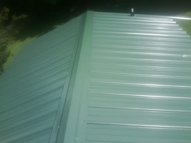 New green metal panels meeting at the ridge of a roof — Flat Roof Repair work by our crew in Codorus