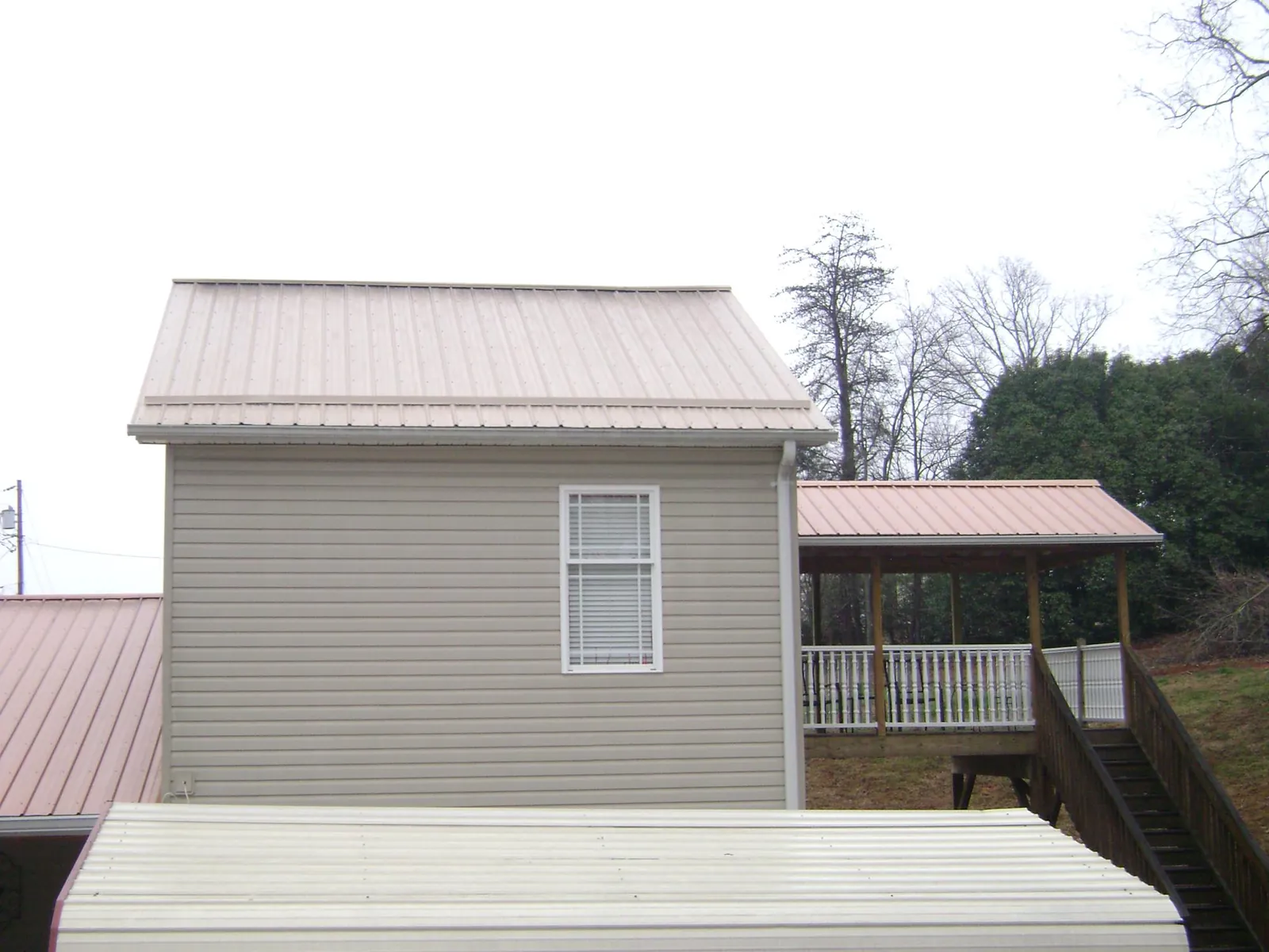 Tan metal roofs on a two story addition and attached porch, from a Roof Replacement job in Codorus