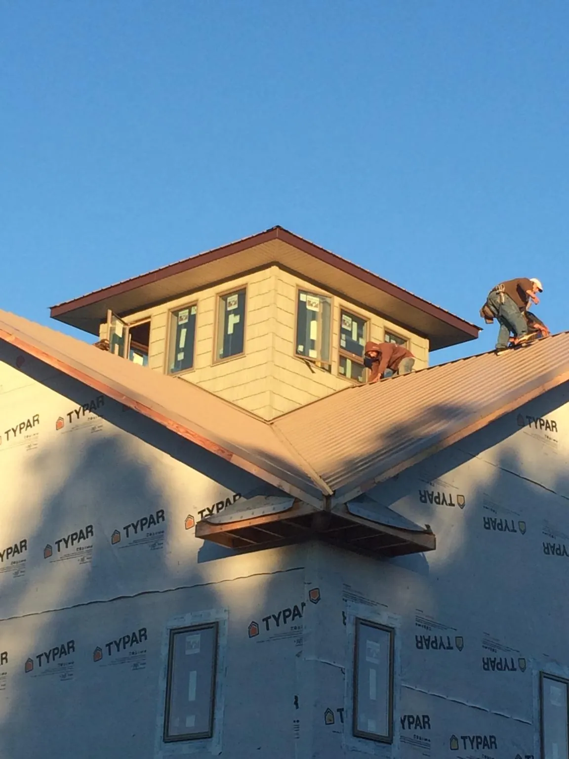 Roofers working around a rooftop cupola on a new metal roof at sunset — Roof Waterproofing in Codorus by Roofing Brothers